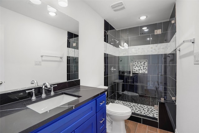 bathroom featuring a shower with door, vanity, and toilet