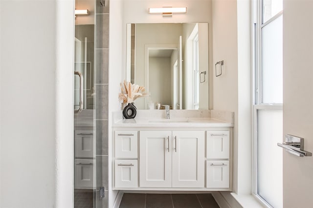 bathroom featuring a shower with door, vanity, tile patterned flooring, and a wealth of natural light