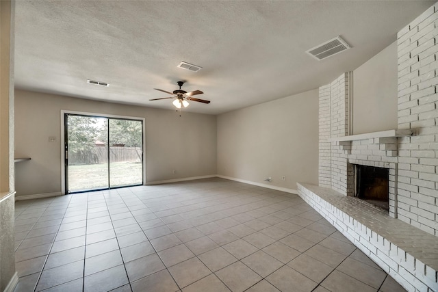 unfurnished living room with ceiling fan, a fireplace, light tile patterned floors, and a textured ceiling