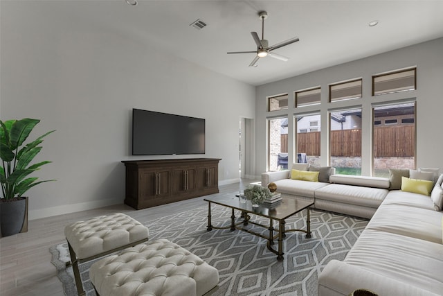 living room with a high ceiling, ceiling fan, and light hardwood / wood-style floors