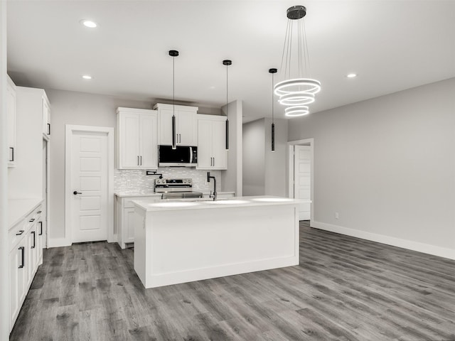 kitchen featuring appliances with stainless steel finishes, backsplash, pendant lighting, white cabinetry, and an island with sink