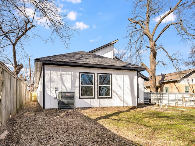 back of house featuring central AC unit and a lawn