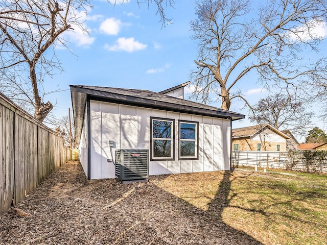 back of property featuring a shed, a yard, and central AC