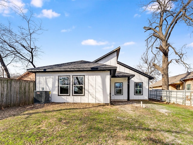 rear view of property with central AC unit and a lawn