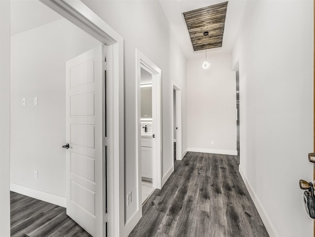 hall featuring a raised ceiling and dark wood-type flooring