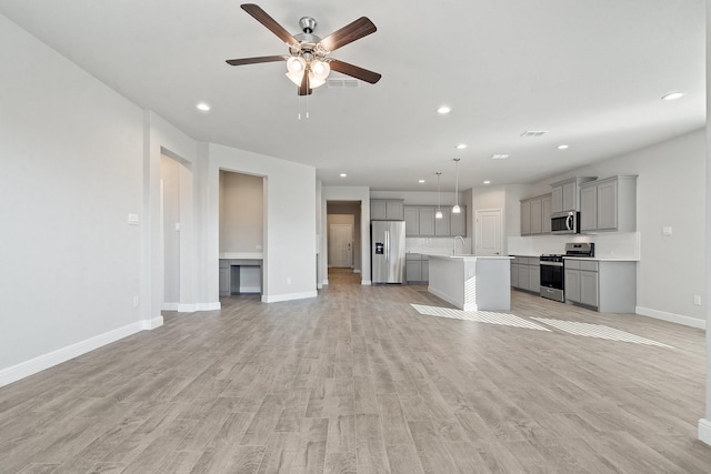 unfurnished living room featuring ceiling fan, light hardwood / wood-style floors, and sink