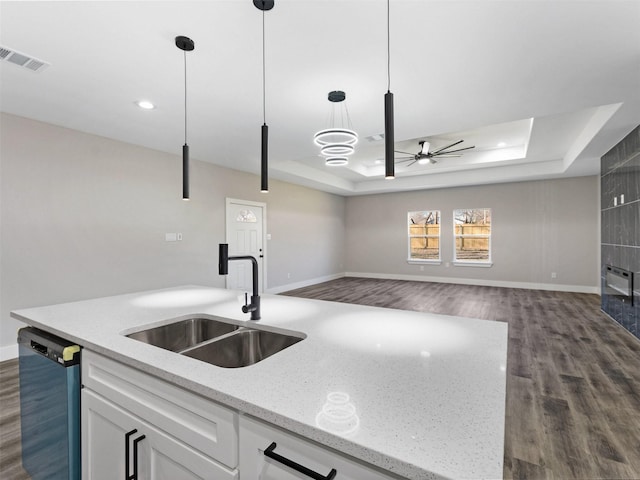 kitchen with white cabinetry, dishwasher, sink, a raised ceiling, and decorative light fixtures