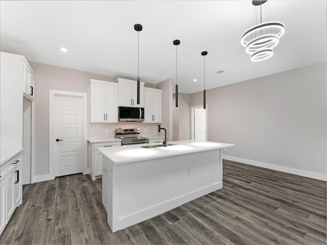 kitchen featuring appliances with stainless steel finishes, sink, a center island with sink, decorative light fixtures, and white cabinetry