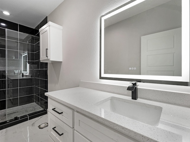 bathroom featuring a tile shower and vanity