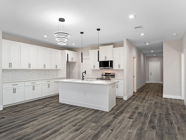 kitchen with pendant lighting, white cabinetry, stainless steel appliances, and an island with sink