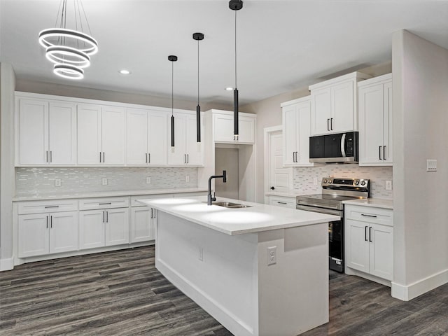 kitchen featuring a kitchen island with sink, white cabinets, decorative light fixtures, and appliances with stainless steel finishes