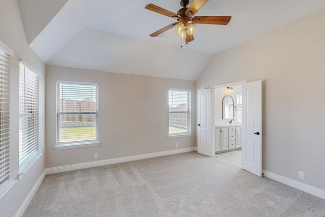 unfurnished bedroom featuring vaulted ceiling, light colored carpet, ceiling fan, and ensuite bathroom