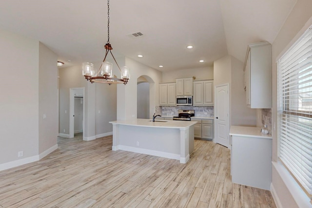 kitchen with sink, tasteful backsplash, hanging light fixtures, light wood-type flooring, and stainless steel appliances