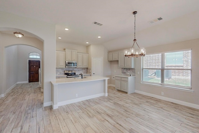 kitchen with sink, stainless steel appliances, tasteful backsplash, pendant lighting, and light hardwood / wood-style floors