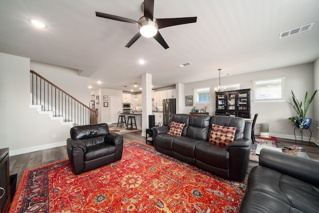 living room with hardwood / wood-style floors and ceiling fan with notable chandelier