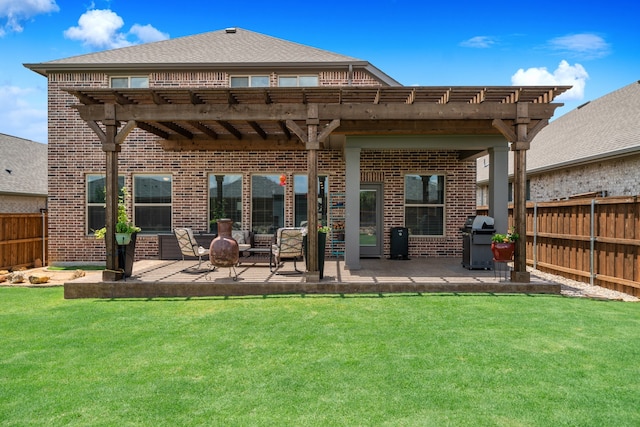 rear view of property featuring a yard, a pergola, and a patio