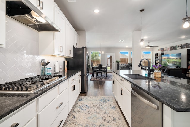 kitchen with dark hardwood / wood-style flooring, stainless steel appliances, sink, pendant lighting, and white cabinets