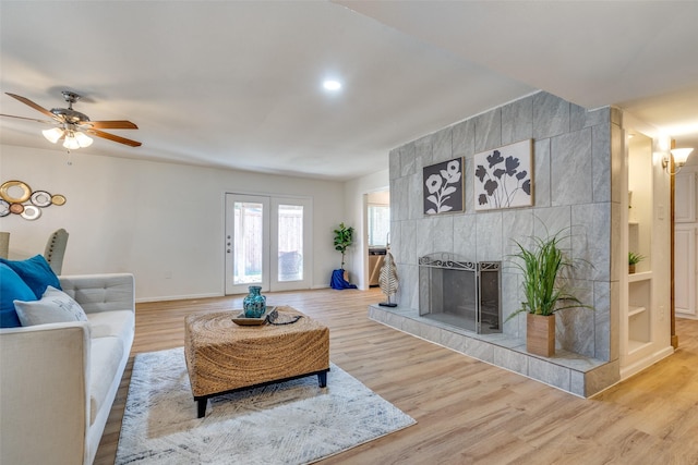 living room featuring hardwood / wood-style floors, ceiling fan, and a tile fireplace