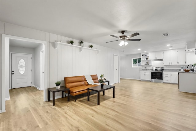 sitting room featuring light wood-type flooring, ceiling fan, and sink