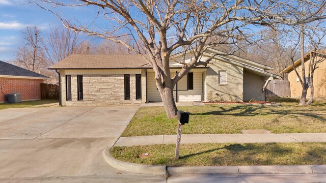 ranch-style home featuring cooling unit and a front yard