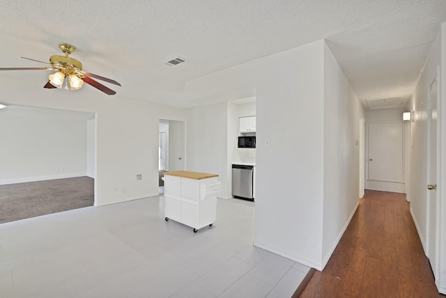 unfurnished living room with ceiling fan, a textured ceiling, and light hardwood / wood-style floors