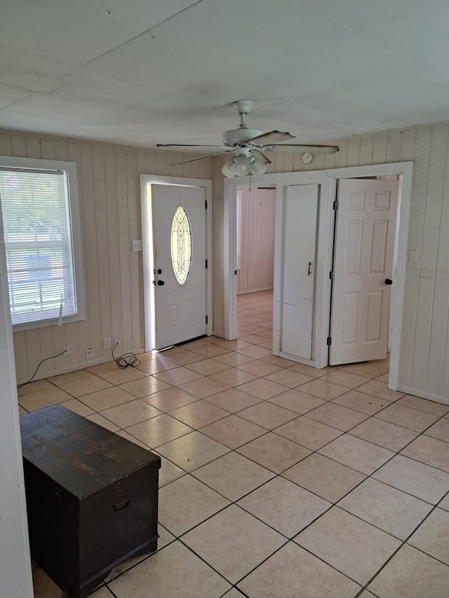 tiled entryway featuring wooden walls, ceiling fan, and a wealth of natural light