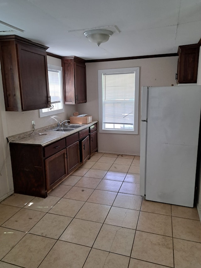 kitchen with sink, light tile patterned flooring, dark brown cabinets, and white refrigerator