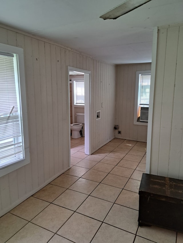 empty room featuring cooling unit, light tile patterned floors, and wooden walls