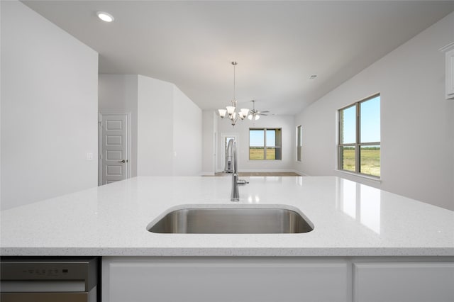 kitchen featuring light stone countertops, pendant lighting, dishwashing machine, and sink