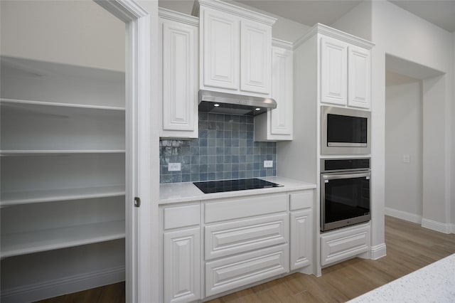 kitchen featuring white cabinets, light wood-type flooring, backsplash, and appliances with stainless steel finishes