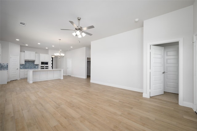 unfurnished living room with light wood-type flooring and ceiling fan with notable chandelier