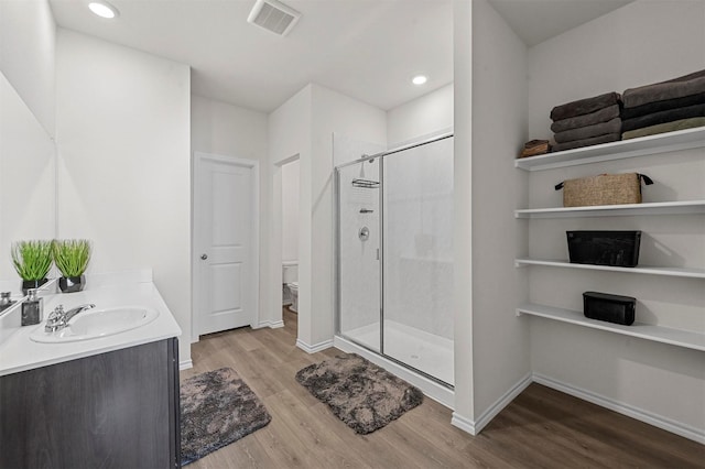 bathroom with hardwood / wood-style flooring, vanity, toilet, and a shower with shower door