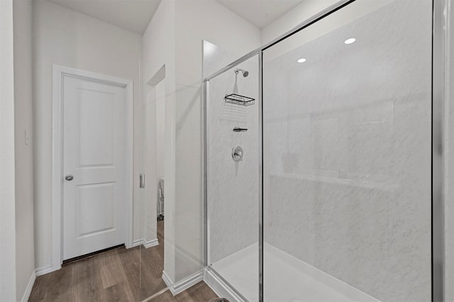 bathroom with wood-type flooring and a shower with shower door