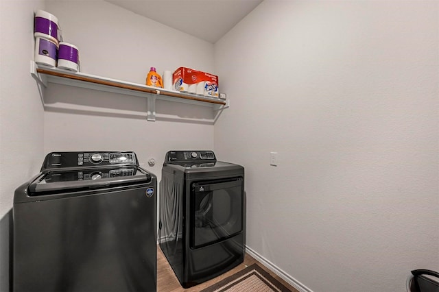 washroom with hardwood / wood-style flooring and washing machine and clothes dryer