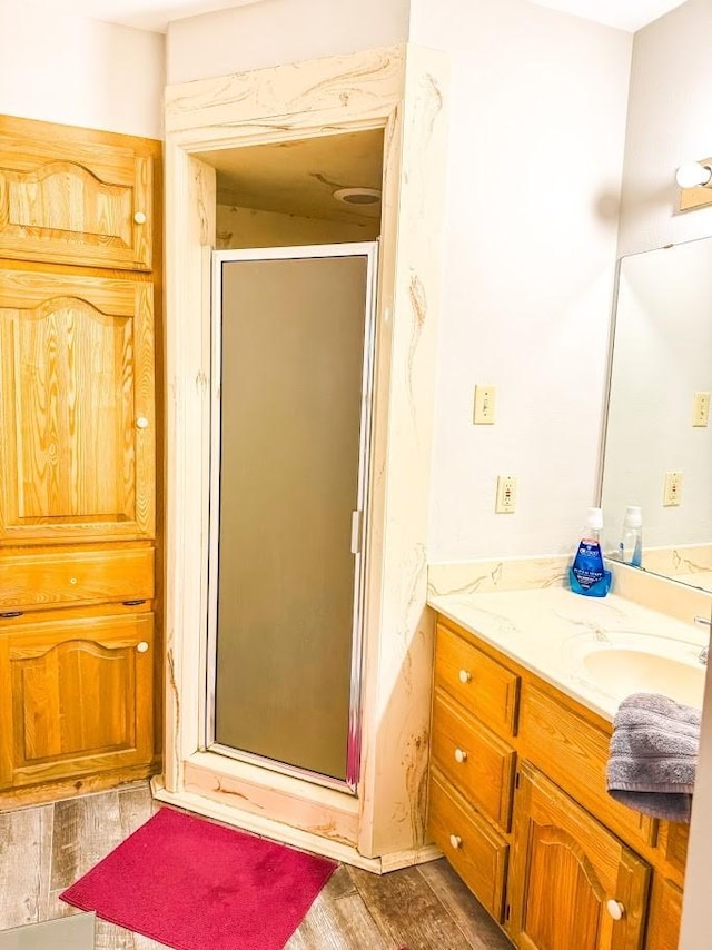 bathroom featuring vanity, a shower with shower door, and wood-type flooring