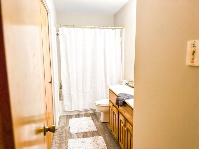 full bathroom featuring hardwood / wood-style flooring, vanity, shower / bathtub combination with curtain, and toilet