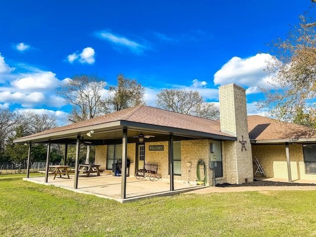 back of property with ceiling fan, a yard, and a patio