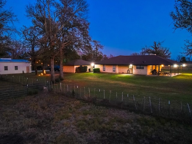 back house at dusk featuring a yard