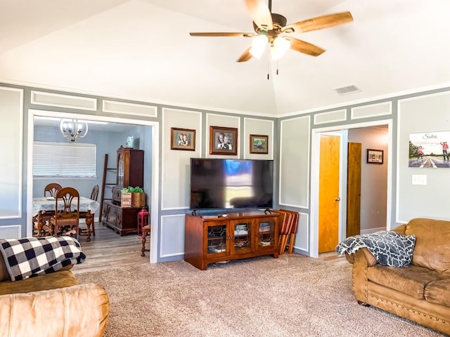 carpeted living room with ceiling fan with notable chandelier and high vaulted ceiling