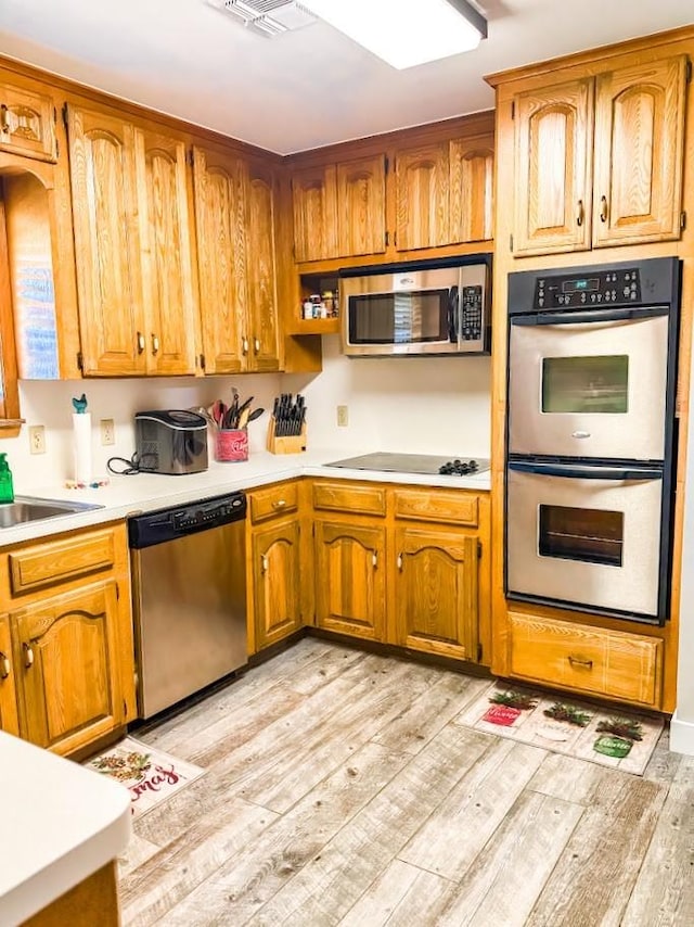 kitchen with sink, stainless steel appliances, and light hardwood / wood-style floors