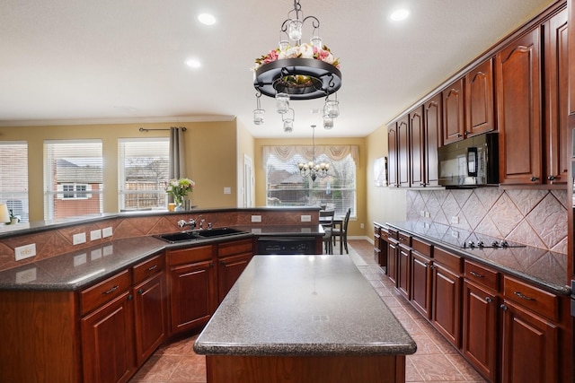 kitchen with a center island, black appliances, sink, tasteful backsplash, and a chandelier