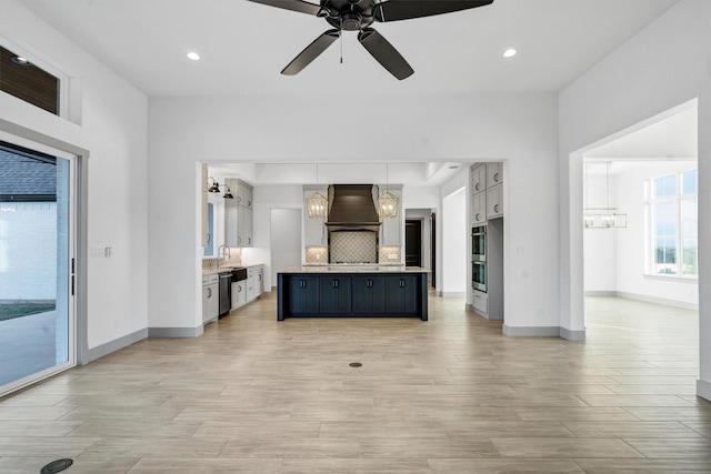 unfurnished living room with ceiling fan with notable chandelier, sink, and light wood-type flooring