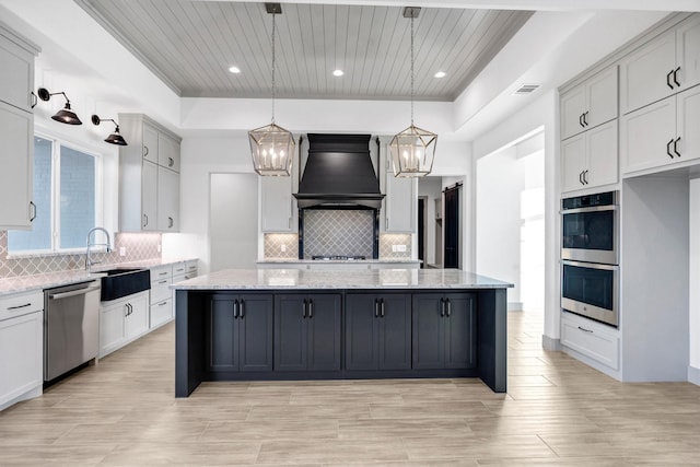 kitchen with pendant lighting, stainless steel appliances, a center island, and custom range hood