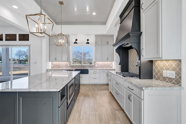 kitchen with light stone countertops, sink, pendant lighting, and a spacious island