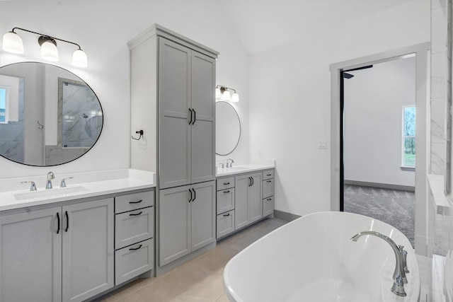 bathroom featuring lofted ceiling, a tub to relax in, and vanity