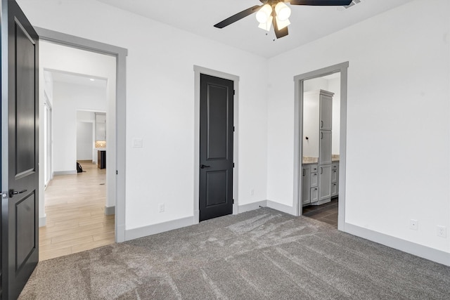 unfurnished bedroom featuring ceiling fan, connected bathroom, and dark carpet