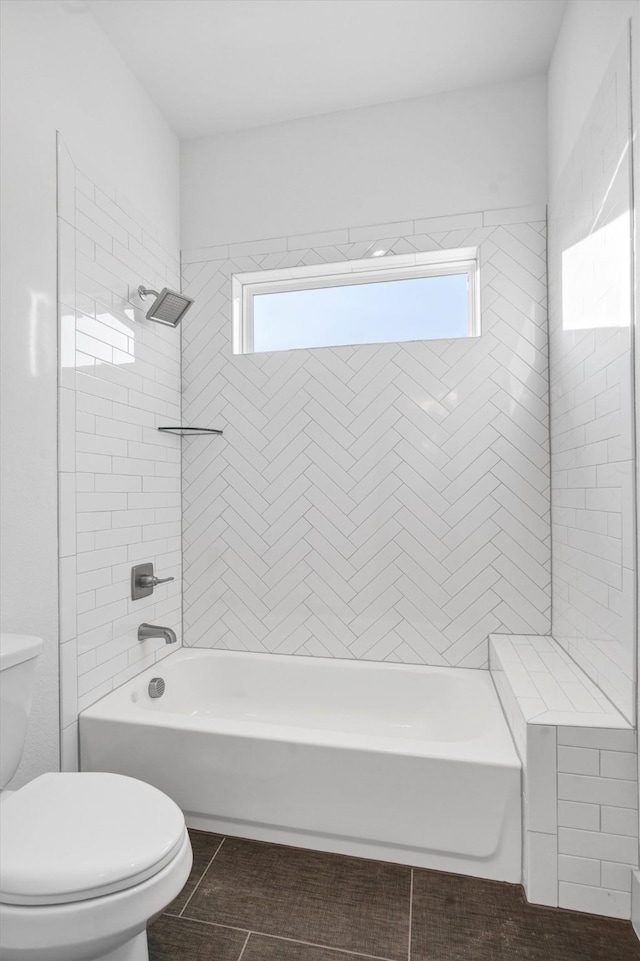 bathroom with tiled shower / bath combo, tile patterned floors, and toilet