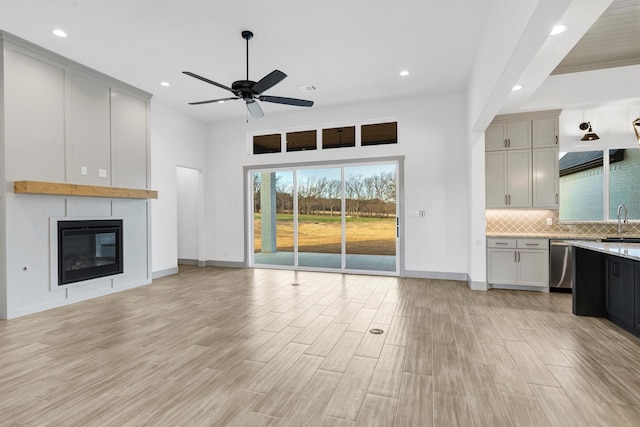 unfurnished living room with sink, a fireplace, and ceiling fan