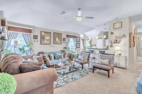 living room with vaulted ceiling, light colored carpet, and ceiling fan