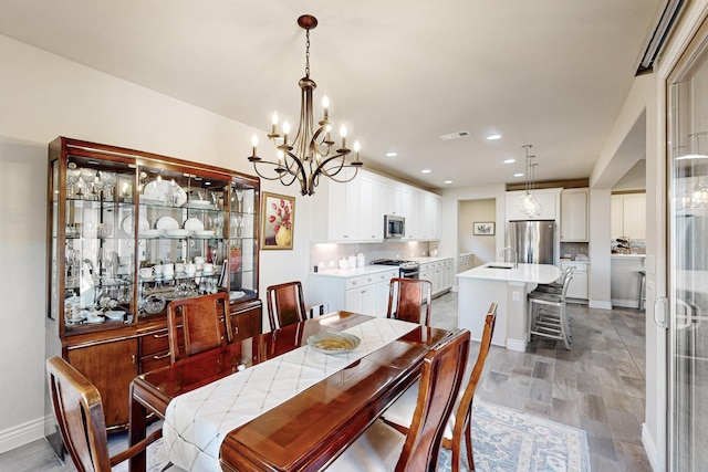 dining space with wood-type flooring, sink, and a notable chandelier